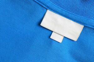 leer Weiß Wäsche Pflege Kleider Etikette auf Blau Hemd Stoff Textur Hintergrund foto