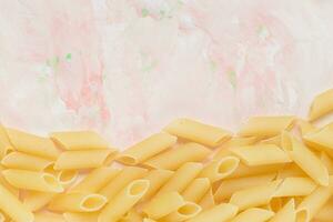 Stapel von roh traditionell Italienisch Penne Pasta auf rosa Hintergrund. Nahaufnahme, Kopieren Raum foto