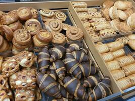 frisch gebacken Süss gefroren Puff Mürbeteig Gebäck mit Marmelade und Sahne Käse im Bäckerei. Schokolade Croissants, Pudding und Zimt Rollen im Lebensmittelgeschäft speichern. frisch Dessert oder Nachmittag Snack foto