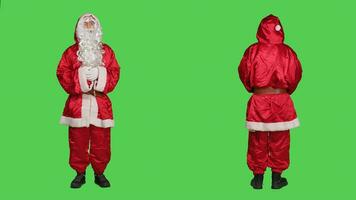 Mann Schauspielkunst mögen Santa im Kostüm Sprichwort ho ho hallo, porträtieren Dezember berühmt Charakter zum Weihnachten Vorabend Feier. Heilige Nick mit Hut und Bart Stehen Über voll Körper grüner Bildschirm. foto