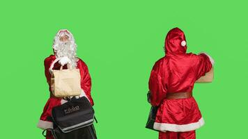 froh Santa claus Person liefern Essen im Papier Tasche, Tragen Thermal- Rucksack während er ist tragen traditionell Urlaub Kostüm. Mann im festlich rot und Weiß Anzug, grüner Bildschirm Hintergrund. foto