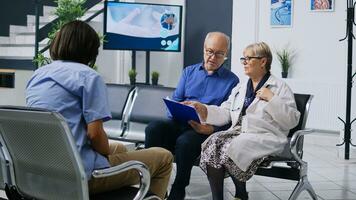 Alten geduldig haben Untersuchung Besuch Untersuchung im Krankenhaus warten Bereich, Füllung medizinisch Unterlagen. Senior Mann diskutieren Gesundheit Pflege Behandlung mit Arzt Arzt im Empfangshalle. Medizin Konzept foto