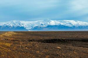 Herrlich Hochland Aussicht im isländisch Region, mit Schnee bedeckt Berge und gefroren Weiden im Distanz. Straßenrand malerisch Fahrbahn mit Nord Landschaft von Hügel und Felder im Island. foto