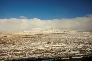 winterlich Landschaft mit eisig kalt Natur im isländisch Region, fest schneebedeckt Berge und gefroren Felder. Winter Wunderland Straßenrand Landschaft mit Hochland und Hügel, szenisch Route. foto