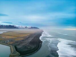 berühmt magisch schwarz Sand Strand, atlantisch Ozean Wellen abstürzen auf isländisch Küste Erstellen schön Landschaft. Drohne Schuss von Fantastisch nordisch Landschaft, stark Gezeiten mit Arktis Wetter. foto