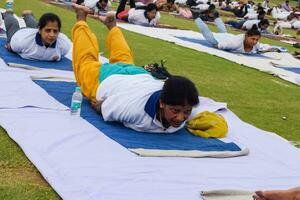 Neu Delhi, Indien, Juni 21, 2023 - - Gruppe Yoga Übung Session zum Menschen beim Yamuna Sport Komplex im Delhi auf International Yoga Tag, groß Gruppe von Erwachsene Teilnahme Yoga Klasse im Kricket Stadion foto