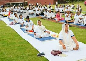 Neu Delhi, Indien, Juni 21, 2023 - - Gruppe Yoga Übung Session zum Menschen beim Yamuna Sport Komplex im Delhi auf International Yoga Tag, groß Gruppe von Erwachsene Teilnahme Yoga Klasse im Kricket Stadion foto