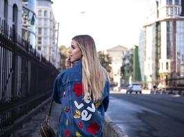 süßes blondes Teen mit wallendem Haar in einer Jeansjacke auf der Brücke foto