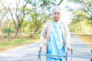 asiatische ältere Frau geduldig Spaziergang mit Gehhilfe im Park