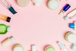 rahmen aus kunststoff-körperpflegeflasche flach lag zusammensetzung mit kosmetischen produkten auf rosa hintergrund leerraum für ihr design. satz weißer kosmetikbehälter, draufsicht mit kopierraum foto