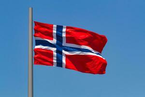 norwegisch Flagge winken im das Wind gegen Blau Himmel. foto