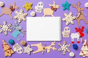 festliche dekorationen und spielzeug auf lila hintergrund. Draufsicht des Notizbuchs. Frohe Weihnachten-Konzept foto