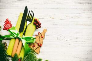 Draufsicht auf Gabel und Messer auf Serviette mit Weihnachtsschmuck und Neujahrsbaum auf Holzhintergrund. feiertags- und festliches konzept mit kopienraum foto