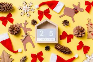 weihnachtsgelber hintergrund mit weihnachtsspielzeug und dekorationen. Draufsicht auf Holzkalender. der fünfundzwanzigste dezember. Frohe Weihnachten-Konzept foto