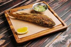 gebraten Fisch auf hölzern Tafel mit würzig Soße foto