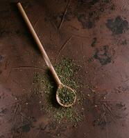 ein Stapel von ein Grün würzen mischen getrocknet Gemüse und Kräuter auf hölzern Löffel foto
