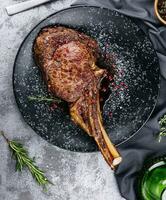 gegrillt Schweinefleisch Steak mit Knochen im Soße auf schwarz Teller foto