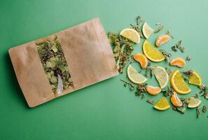 Blatt Tee verschüttet aus von ein Papier Paket mit Orange und Mandarine Scheiben foto