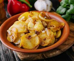 gebraten Kartoffeln mit Zwiebeln auf hölzern Tablett foto