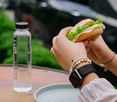 Frau Essen Burger Sandwich beim draussen Terrasse Bistro foto