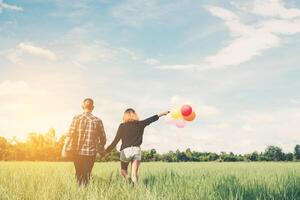 Rückseite des glücklichen jungen asiatischen Paares, das Ballon hält und zusammen geht. foto