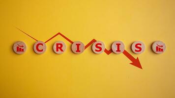 hölzern Würfel mit das Wort Krise und ein rot Pfeil Nieder auf ein Gelb Hintergrund, Geschäft finanziell Verlust, Krise Konzept. foto