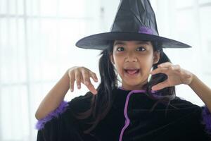 glücklich asiatisch Kind Mädchen im ein Hexe Kostüm zu Halloween. Trick oder behandeln. Kinder Trick oder behandeln. foto