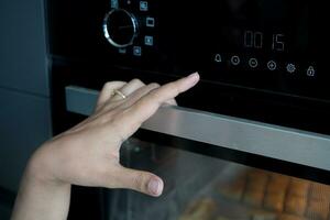 Frau Hand Rahmen Temperatur Steuerung auf Ofen. foto