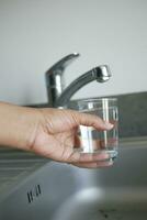 Wasser Gießen von ein Wasserhahn Zapfhahn im ein Glas, Trinken rein Wasser Konzept foto