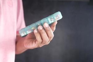Männerhände, die Medizin aus einer Pillendose nehmen foto