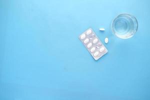Draufsicht der Pille Blisterpackung und Glas auf Wasser auf Blau
