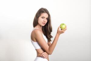 Schönheitsfrau, die grünen Apfel hält, während sie auf Weiß isoliert ist foto