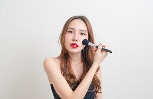 Porträt schöne asiatische Frau mit Make-up-Pinsel auf weißem Hintergrund foto