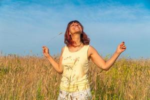 lächelnde Frau im Sommerfeld bei Sonnenuntergang, Positivitätskonzept foto