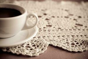 Weiß Tasse mit schwarz Kaffee auf ein handgemacht Tischdecke foto