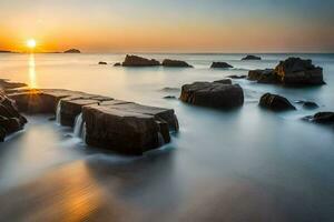 ein lange Exposition fotografieren von Felsen auf das Strand beim Sonnenuntergang. KI-generiert foto