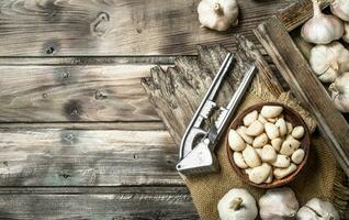 Knoblauch auf ein Schneiden Tafel mit ein Knoblauch Drücken Sie. foto