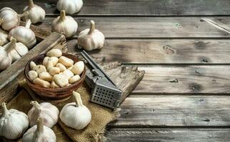 Knoblauch auf ein Schneiden Tafel mit ein Knoblauch Drücken Sie. foto