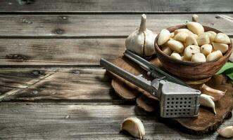 Nelken von frisch Knoblauch auf ein Schneiden Tafel mit ein Knoblauch Drücken Sie. foto