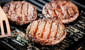 Kochen ein köstlich gegrillt Burger auf ein schwenken mit Öl Blasen. foto