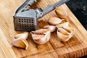 Nelken von Knoblauch auf ein Schneiden Tafel mit ein Knoblauch Drücken Sie. foto