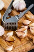 Nelken von Knoblauch auf ein Schneiden Tafel mit ein Knoblauch Drücken Sie. foto