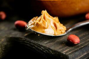 Erdnuss Butter im ein Löffel auf ein Schneiden Tafel. foto