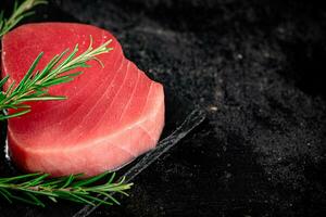 roh Thunfisch auf ein Stein Tafel mit Rosmarin. foto