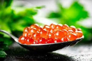 ein voll Löffel von rot Kaviar auf das Tabelle mit Petersilie. foto