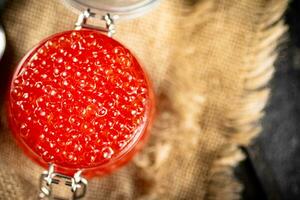 ein Glas Krug mit rot Kaviar auf Sackleinen. foto