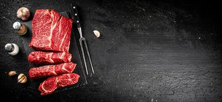 Stücke von roh Rindfleisch auf ein Stein Tafel. foto