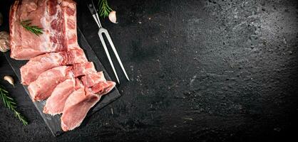 gehackt roh Schweinefleisch auf ein Stein Tafel mit Rosmarin und Knoblauch. foto