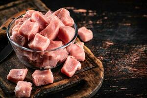 Stücke von roh Schweinefleisch im ein Schüssel auf ein Schneiden Tafel. foto