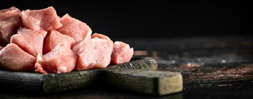 Stücke von roh Schweinefleisch auf ein Schneiden Tafel auf das Tisch. foto